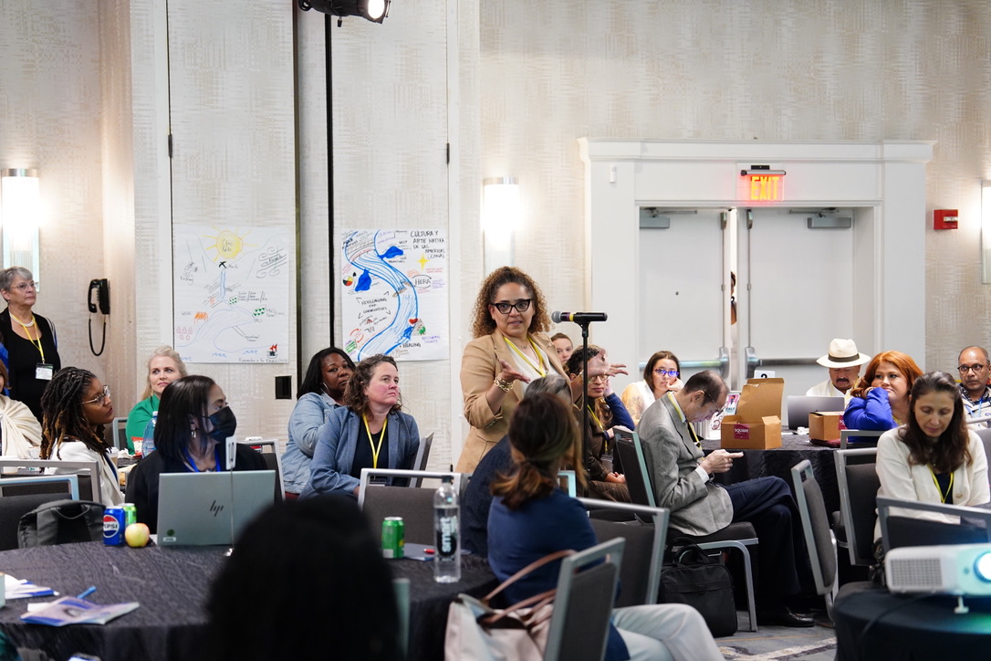 A speaker addressing attendees at a community-led research symposium